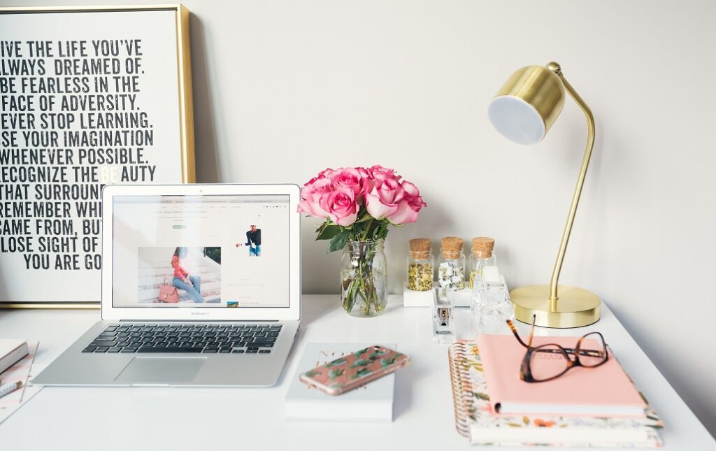 Office space organized with flowers, keyboard, notebooks, and lamp.