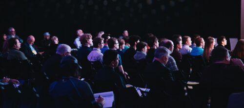 An audience of people taking notes