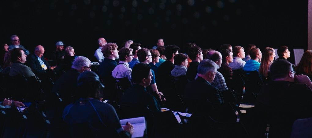 An audience of people taking notes