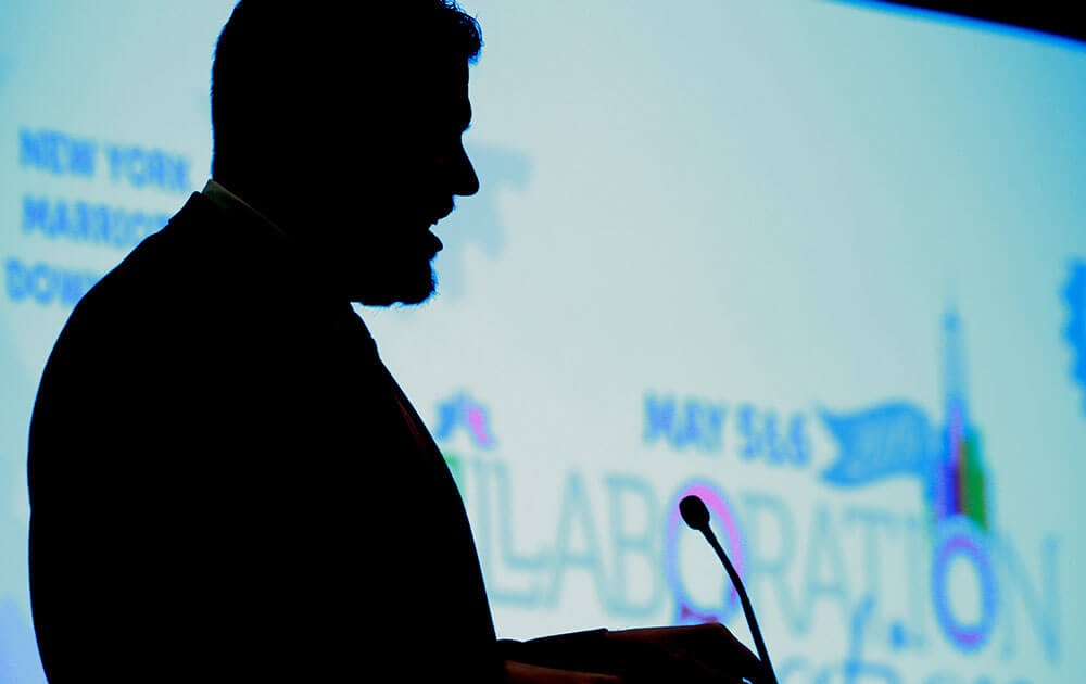 Silhouette of man speaking in front of a microphone